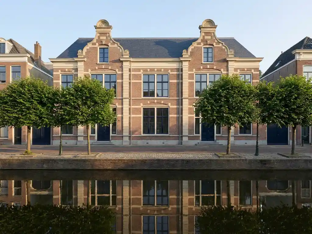 Gerestaurde Amsterdamse grachtenpand met klassieke Nederlandse architectuur weerspiegeld in stil kanaalwater
